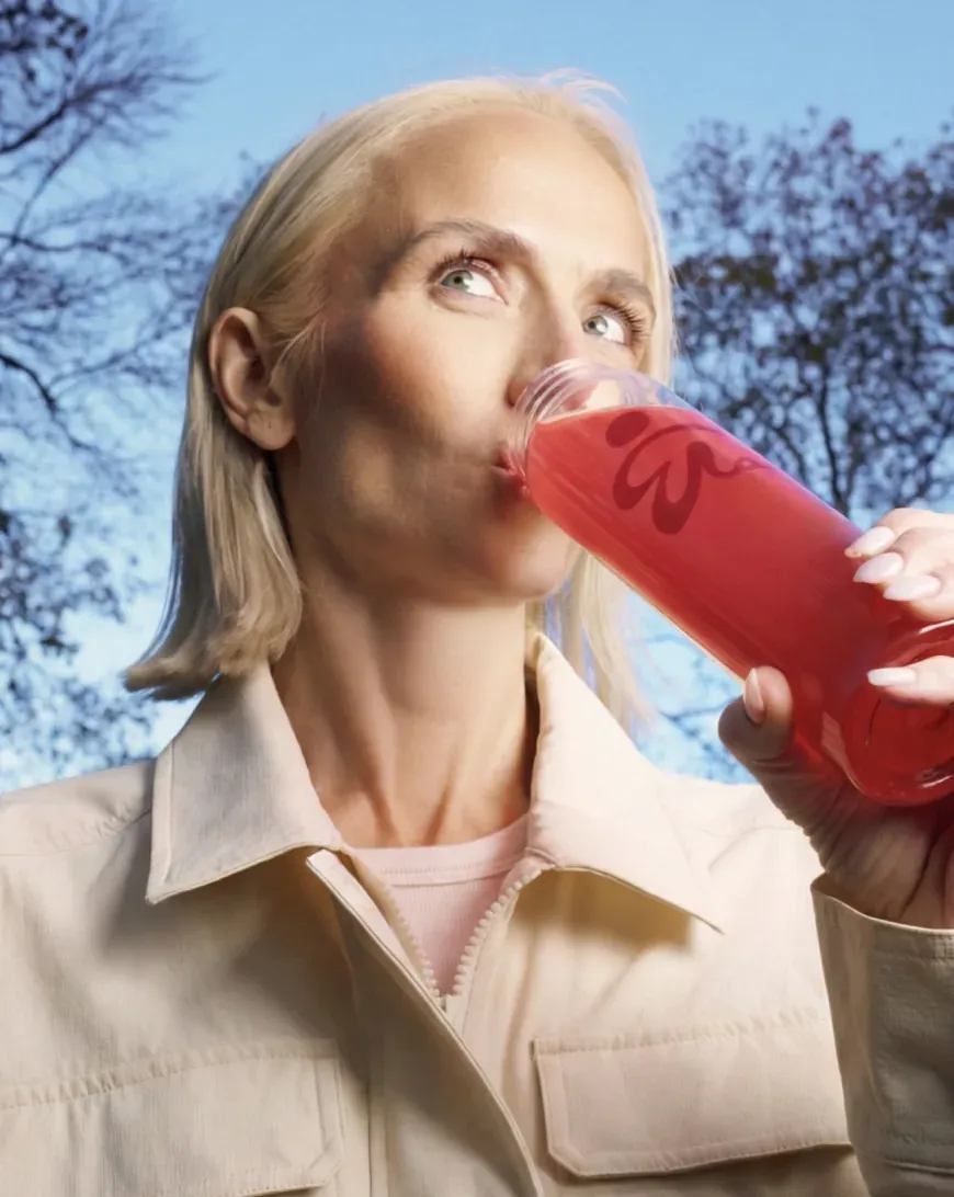 Woman drinking a red ByEla drink outdoors